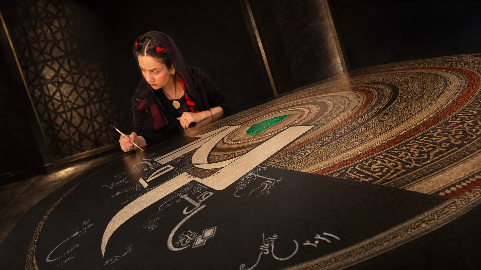Ayesha Kamal applying detailed brushwork to an original painting