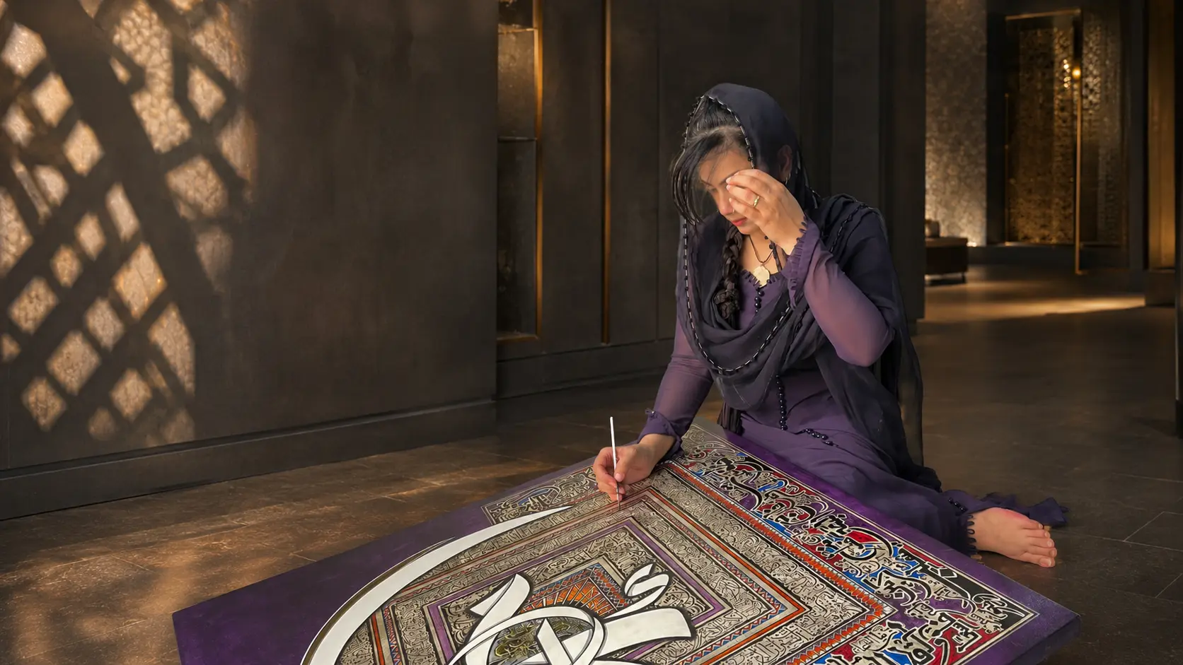 Ayesha Kamal creating an original calligraphic painting in her studio